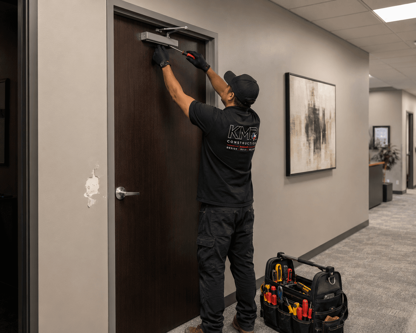KMR Construction handyman adjusting a door closer in a Class-A office corridor